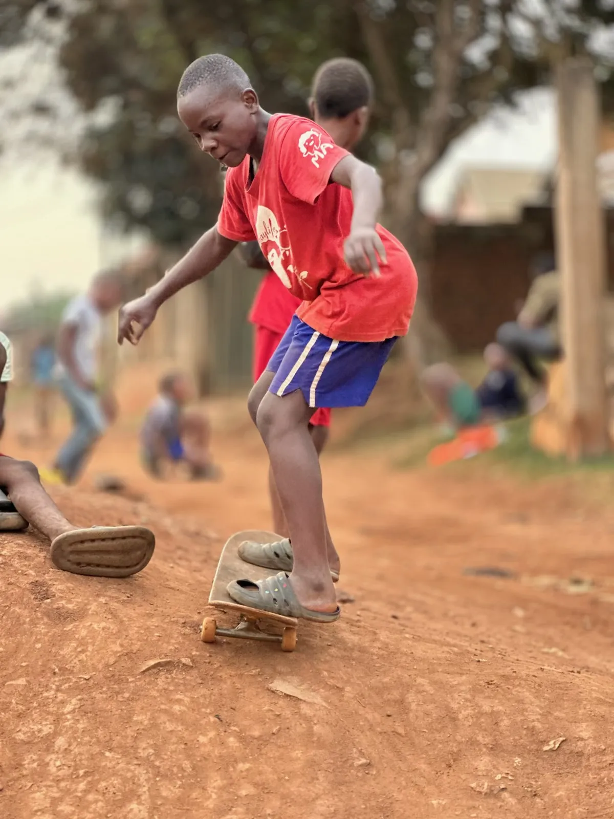 Child skateboarding on a dirt road in Kampala