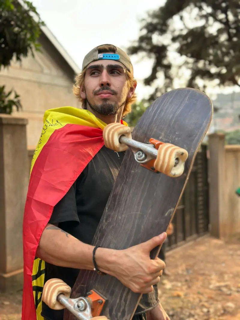Jason carrying a skateboard draped in the Ugandan flag